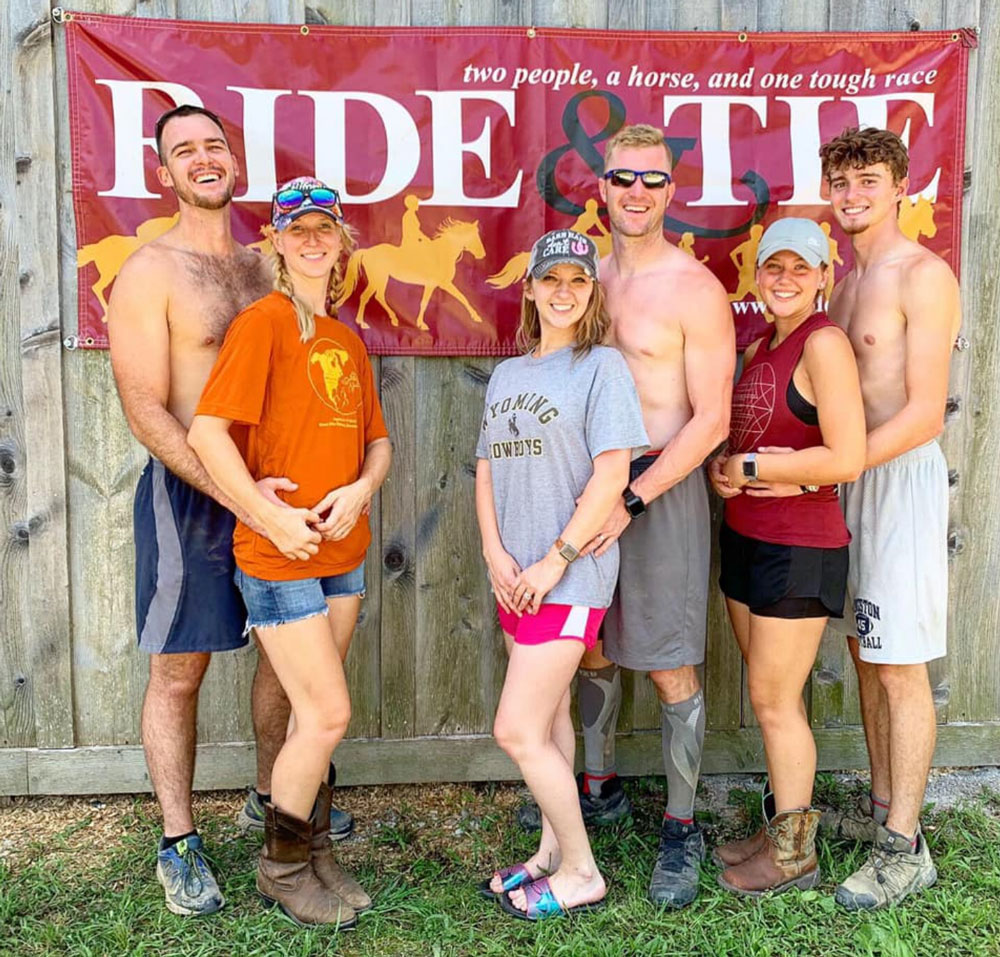 Image of six people in front of a Ride & Tie banner.